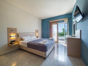 a bedroom with a bed with blue walls and a television at Paradise Resort in Finikounta