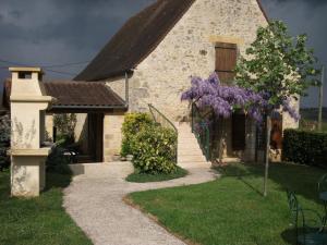 una casa con un árbol de flores púrpura delante de ella en Gîte Daglan, 3 pièces, 4 personnes - FR-1-616-77, en Daglan