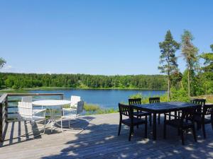 a deck with a table and chairs and a lake at 6 person holiday home in ÅKERSBERGA-By Traum in Åkersberga