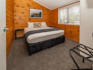 1 dormitorio con 1 cama en una habitación de madera en Tasman Holiday Parks - Rotorua en Rotorua