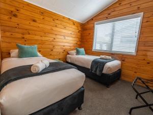 two beds in a room with wooden walls at Tasman Holiday Parks - Rotorua in Rotorua