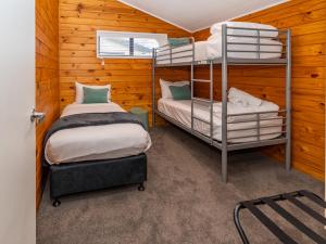 two bunk beds in a room with wooden walls at Tasman Holiday Parks - Rotorua in Rotorua