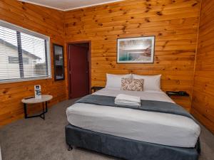 a bedroom with a large bed in a wooden wall at Tasman Holiday Parks - Rotorua in Rotorua
