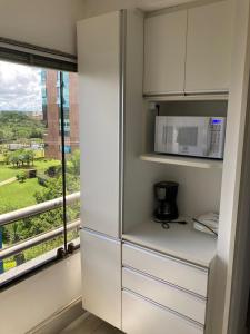 a kitchen with a microwave and a window at Flats Asa Norte CLN 213 by CentoEdez in Brasília