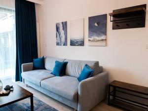 ein Wohnzimmer mit einem Sofa und blauen Kissen in der Unterkunft A comfortable apartment very close to the seaside beach, Niechorze in Niechorze