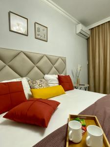 - une chambre dotée d'un grand lit avec des oreillers rouges et jaunes dans l'établissement Mangilik Cozy Apartment, à Astana