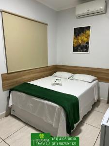 um quarto com uma cama branca e um cobertor verde em Hotel Trevo Caruaru em Caruaru