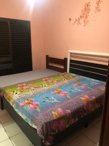 a bed with a bedspread with flowers on it at Guarujá Enseada in Guarujá