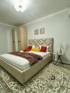 - une chambre dotée d'un grand lit avec des oreillers rouges et jaunes dans l'établissement Mangilik Cozy Apartment, à Astana