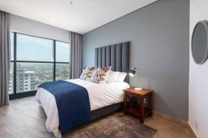 een slaapkamer met een bed en een groot raam bij Oceans Umhlanga 2 Bedroom Accommodation in Durban