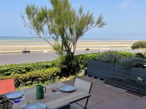 a table with wine glasses on a patio near the beach at Appartement Cabourg, 2 pièces, 4 personnes - FR-1-794-82 in Cabourg