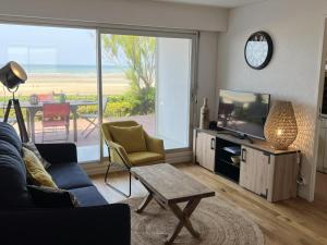 a living room with a couch and a tv and a table at Appartement Cabourg, 2 pièces, 4 personnes - FR-1-487-258 in Cabourg