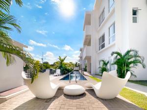 a view of a building with white chairs and a pool at Pura Vida Apartment with nice pool walking distance to the heart of Jaco in Jacó