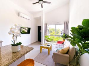 een woonkamer met een bank en een aantal planten bij Pura Vida Apartment with nice pool walking distance to the heart of Jaco in Jacó