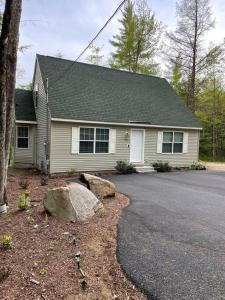 a house with a rock in front of a driveway at Bungalow near Winnisquam Lake! Sleeps 14 in Sanbornton