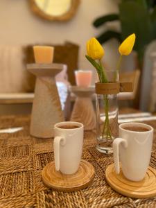 duas chávenas de café e um vaso com flores amarelas em alba otel em Ildır