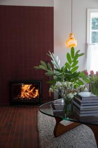 a living room with a glass table and a fireplace at Months and Seasons Design-led Country House in Daylesford +35 photos