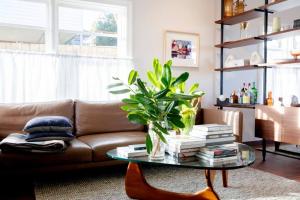 a living room with a couch and a table with books at Months and Seasons Design-led Country House in Daylesford