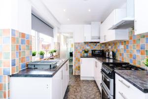 a kitchen with white cabinets and tiles on the wall at Harley House in Parkside