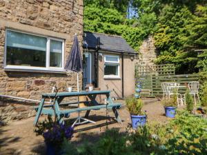 a picnic table in front of a stone house at Hollie Cottage in Haltwhistle