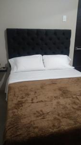 a large bed with a black headboard and white pillows at HOSPEDAJE SAN GABRIEL in Chiclayo