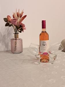 uma garrafa de vinho e um vaso com flores sobre uma mesa em Apartman Zrinka em Jesenice