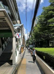 un hombre caminando por una acera al lado de un edificio en High-Class 2BED Condo Just 1-Step from BTS ONNUT en Bangkok