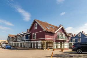 un grande edificio rosso in un parcheggio di Nida Home by Z-EDA a Nida