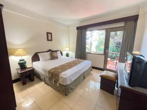 a bedroom with a bed and a tv in it at Beach Apartment inside Resort Walking Distance to the beach in Seminyak