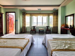 two beds in a room with green walls and windows at Nhật Anh Hotel Cát Bà in Cat Ba