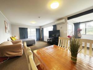 een woonkamer met een tafel, een bank en een televisie bij Kingswood Manor Motel in Whangarei