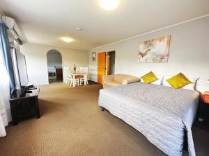 a bedroom with a bed and a table and a chair at Kingswood Manor Motel in Whangarei