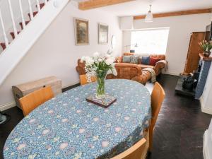 einen Esstisch mit einer Blumenvase darauf in der Unterkunft 3 Bridge Villas in Narberth