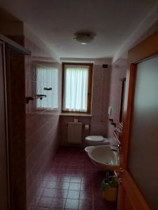 a bathroom with two sinks and a toilet and a window at Albergo Scoiattolo in Tret