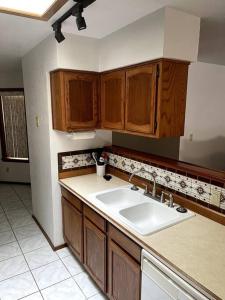 a kitchen with a white sink and wooden cabinets at Townhouse, two car garage, fireplace back yard in Las Cruces