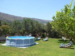 a pool in a yard with two people laying on the grass at Villa Alexia in Souda