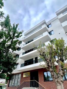 a white building with a tree in front of it at Apartaments PopDan Residence by the Sea in Eforie Nord