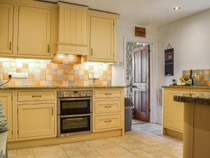 a kitchen with yellow cabinets and a sink at Chapel House in Bourton on the Water