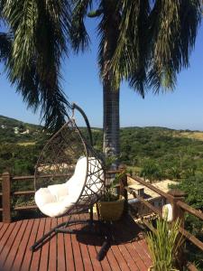 una silla mecedora en una terraza con una palmera en Pousada Mar'Tito Forno, en Búzios