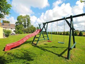 a playground with a red slide in a field at Stylish house in the countryside 5 km from the sea in Darłowo