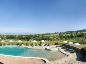 a large swimming pool with chairs and umbrellas at Holiday apartment on a farm in Umbria in Bettona