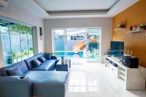 ein Wohnzimmer mit einem blauen Sofa und einer Rutsche in der Unterkunft AK Pool Villa Jomtien 216 in Nong Prue