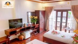 a bedroom with a desk and a bed and a television at Mekong Charm Riverside in Luang Prabang