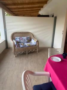 einen Korbstuhl auf einer Terrasse mit einem Tisch in der Unterkunft Il Nespolo Casa Vacanze a due passi dal mare in Olbia