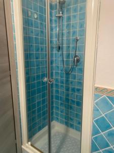 eine blau geflieste Dusche mit einer Glasdusche hinter der Tür in der Unterkunft Il Nespolo Casa Vacanze a due passi dal mare in Olbia