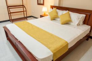 a bedroom with a large bed with yellow and white pillows at Transit Trails in Katunayake