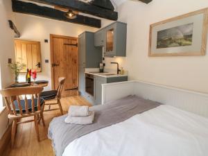 a bedroom with a bed and a table and a kitchen at Woodbine Retreat in Buxton