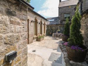 a stone building with a courtyard with a table and chairs at Woodbine Retreat in Buxton