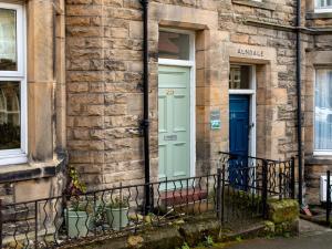 a stone building with a blue door and potted plants at Longshore in Alnmouth