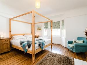 a bedroom with a canopy bed and a blue chair at Longshore in Alnmouth